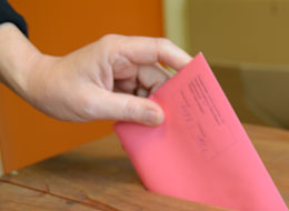 Ein Wahlbrief wird in die Wahlurne gesteckt