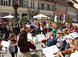Musikschüler mit Streichinstrumenten auf dem Marktplatz bei einer Aufführung