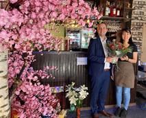 Der Bürgermeister überreicht der Besitzerin des neuen Lokals einen Blumenstrauß im
