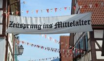Mit Wimpeln geschmückte Fachwerkhäuser und Banner 'Zeitsprung ins Mittelalter'