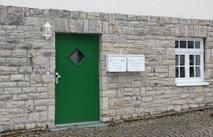 Grüne Haustür im Maurerwerk, Briefkästen, ein Sprossenfenster