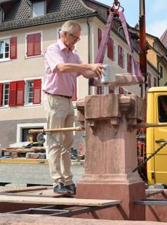 Bürgermeister Dieter Knittel setzt die neue Zeitkapsel in den Metzgerbrunnen ein.
