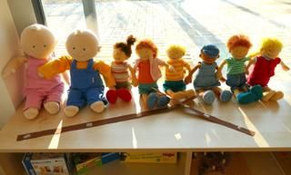 Archivbild Kindergarten. Mehere Stoffpuppen in einer Reihe sitzend.