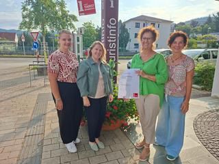Das Team der Touristinfo Gernsbach freut sich über die erneute Auszeichnung des DTV. 4 Damen vor der Säule mit Aufschrift touristinfo, daneben die i-Marke