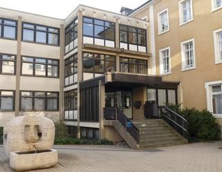 Ein Gebäude mit einem abstrakten Brunnen davor.