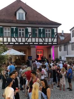 EInige Menschen in einer Sommernacht bei stimmungsvollen Licht vor dem Kornhaus in der Gernsbacher Altsttadt
