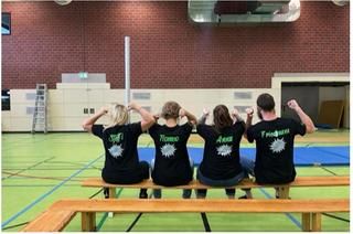 Das professionelle Jugendhausteam Rückenansicht von 4 Personen, die in einer Turnhalle auf einer Bank sitzen