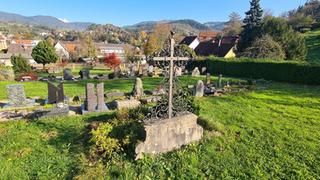 Zu sehen ist der Friedhof mit Gräbern und Grabsteinen und Wiese.