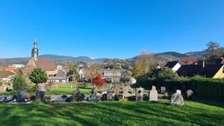 Wiese, Gräber mit Grabsteinen, Häuser, Kirche.