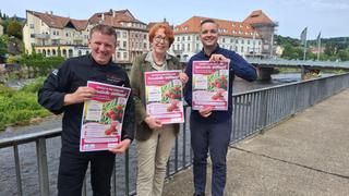 v. l.. n. r. Bernd Werner, Bürgermeister Christ, Sabine Katz 3 Personen stehen an der Flusspromenade halten und halten Plakate hoch.