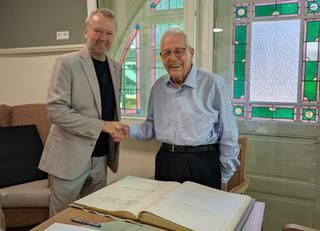 Bürgermeister-Stellvertreter Meyer gratuliert Karl Vollmer Ein Mann gratuliert dem 100-jährigen zum Geburtstag, davor das Goldene Buch