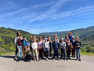 Eine Schulklasse mit Lehrerin und dem Ziegenstall-Führer, Hintergrund Wald