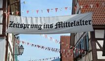 Mit Wimpeln geschmückte Fachwerkhäuser und Banner 'Zeitsprung ins Mittelalter'