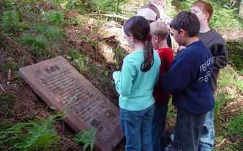  Kinder lesen die in Sandstein gemeißelte Beschreibung des Naturerlebniswegs 