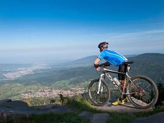Mountainbiker mit seinem Rad auf Felsen genießt den Ausblick auf das Murgtal