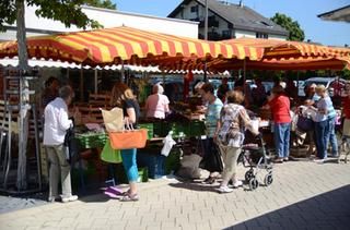 Viele Gäste tummeln sich am Marktstand mit Obst und Gemüse