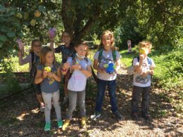 Kinder mit ihren selbst gestalteten Projekten unter einem Baum