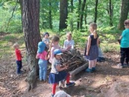 Kinder der Kindertagesstätte Rockertstrolche spielen im Wald Neben einem Baum spielen Kinder mit Ästen