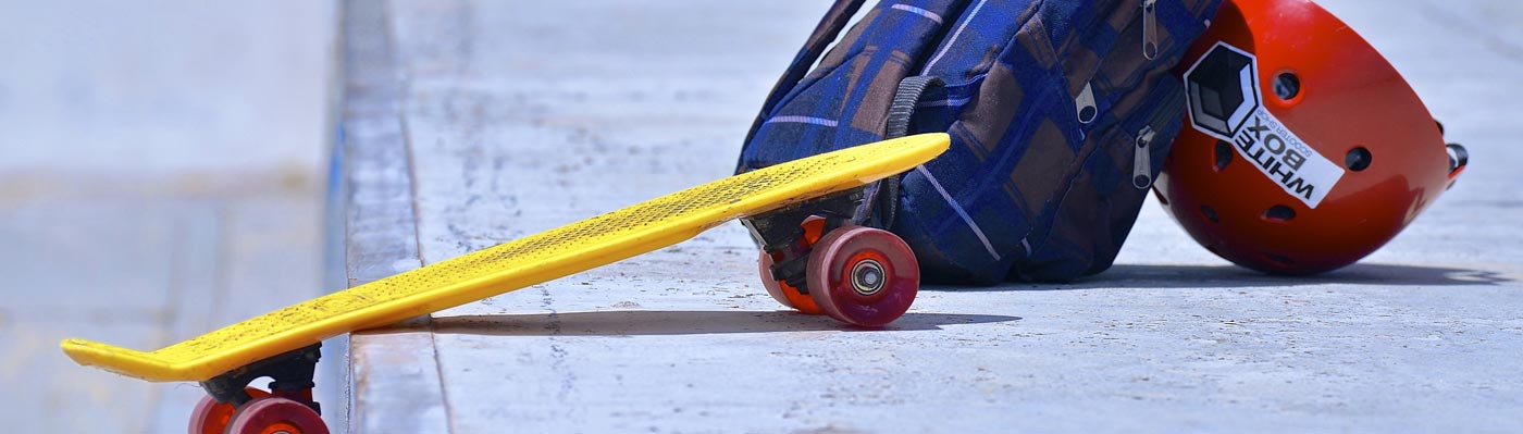 Nahaufnahme Skateboard mit Rucksack und Helm