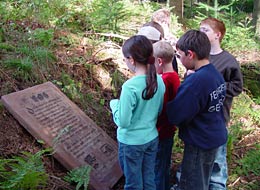 weiter zum Naturerlebnisweg Kinder lesen die in Sandstein gemeißelte Beschreibung des Naturerlebniswegs