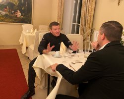 2 Männer im Gespräch am Tisch.