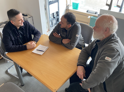 Drei Männer an einem Tisch im Gespräch