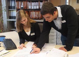 Ausbildung Zwei Auszubildende beugen sich über Akten auf einem Schreibtisch