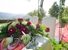 Blumengesteck auf dem Trautisch, zwei weiße Stühle für die Brautleute