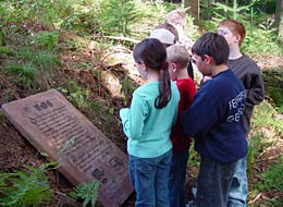 Kinder lesen die in Sandstein gemeißelte Beschreibung des Naturerlebniswegs