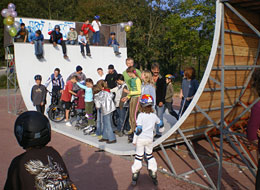 Eine Gruppe Jugendlicher steht mit Inlinskates und Rädern in der Halfpipe
