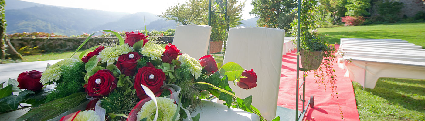 Blumengesteck auf dem Trautisch, zwei weiße Stühle für die Brautleute
