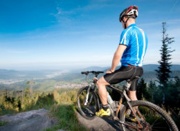 Mountainbiker mit seinem Rad auf Felsen mit Blick ins Murgtal