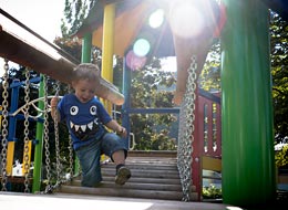 Ein junge auf einem bunten Klettergerüst, auf der Hängebrücke