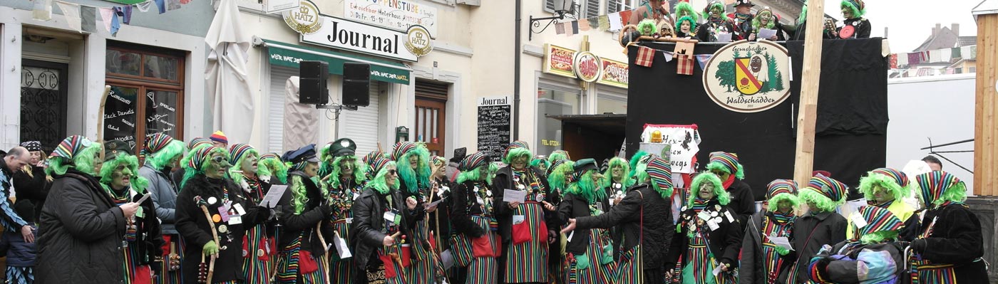 Gernsbacher Bleichexen in ihrem bunten Kostüm mit grüner Perücke am Stadtbuckel