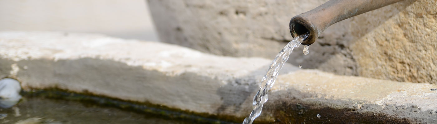 Nahaufnahme Wasser läuft aus Brunnenrohr in den Trog