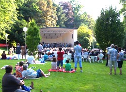weiter zu den Veranstaltungsorten Besucher lauschen gemütlich auf Picknickdecken im Grünen einem Konzert im Kurpark