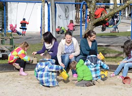 Kinder mit ihren Erzieherinnen im Sandkasten
