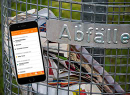 weiter zur Abfallentsorgung Abfallkorb mit Papiermüll und Smartphone mit der Abfall-App im Display