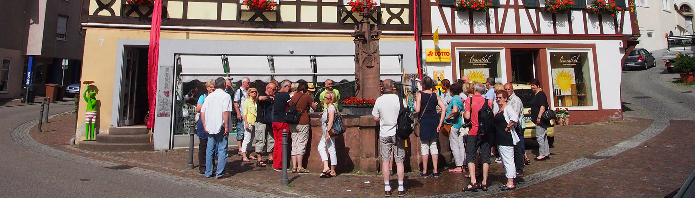 Eine Gruppe von Menschen steht am Brunnen an der Hofstätte bei einer Stadtführung