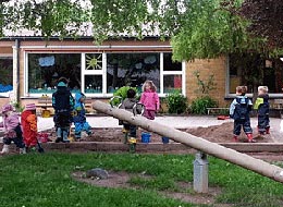 Ev. Kindergarten St. Jakob Außenbereich Kinder spielen im Sandkasten neben einer Wippe.