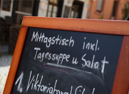 weiter zu den Gastronomiebetrieben Tafel mit Kreideschrift zum Angebot des Restaurants