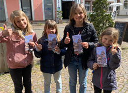 Kinder bei der Altstadt-Rallye 4 Mädchen in der Altstadt in der Hand die Altstadtrallye für Kids zeigen "Daumen hoch"